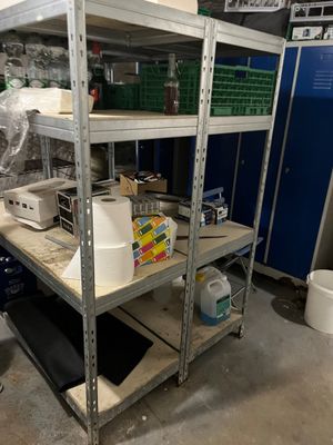 une étagère métallique sur laquelle sont posés de nombreux objets, dans une pièce