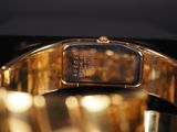 a close up of a gold wrist watch on a black surface