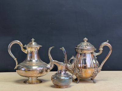 three pieces of silver tea and coffee set sitting on a table