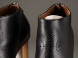 the heel of a pair of black leather ankle boots with laser cut outs