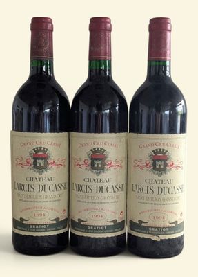 three bottles of red wine sitting next to each other on a white surface