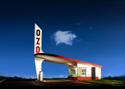 une photo d'une station-service de nuit, avec un ciel bleu en arrière-plan