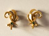 paire de boucles d'oreilles dorées ornées de pierres vertes sur un fond blanc