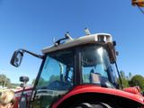 a woman standing next to a red tractor in a parking lot