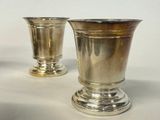 two silver vases sitting on a table with a white background