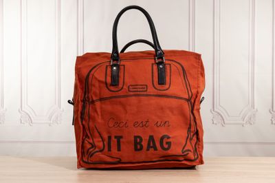 an orange bag sitting on top of a wooden table next to a white wall