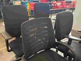 several office chairs are lined up in a warehouse area