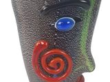 un vase noir orné d'un visage rouge et bleu