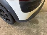 the rear end of a white car with black rims parked in a garage