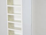 a tall white bookcase with a few shelves on it