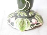 a green vase with a pink flower on top of it