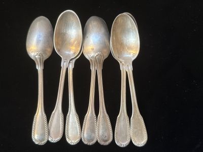 six cuillères en argent sont alignées sur une surface noire