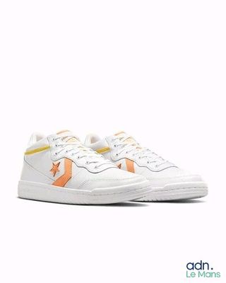 les baskets blanches et orange sont posées sur une surface blanche