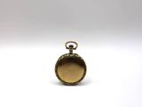 a small gold pocket watch sitting on a white surface