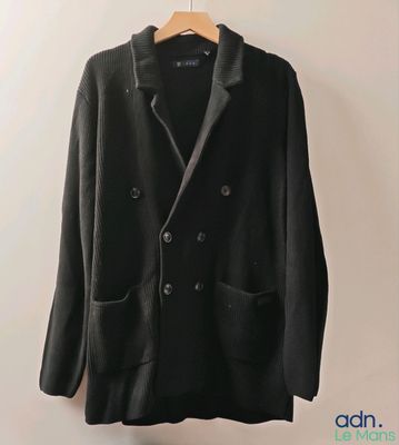 un blazer noir suspendu à un cintre accroché au mur
