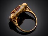 an image of a gold ring with a garnet stone and diamonds