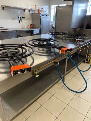 plan de travail en acier inoxydable avec trois brûleurs et un tuyau sur le côté