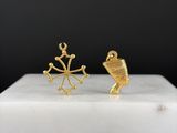 une photo représentant une paire de boucles d'oreilles en or posées sur une surface en marbre