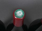 three bottles of red wine are lined up on a black surface