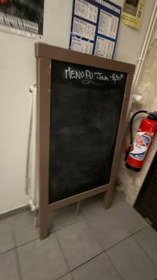 un tableau noir posé par terre près d'un extincteur