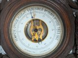a clock that is sitting on a table with a barometer on it