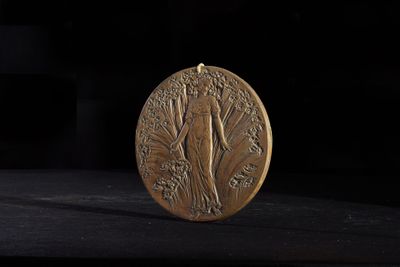 a gold medal on a black surface with a black background