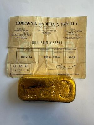 un vieux lingot d'or posé sur une feuille de papier, à côté d'un ticket de caisse