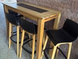 three black chairs sitting at a table with a wooden table top
