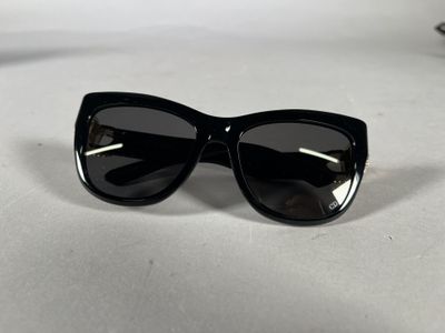 black cat eye sunglasses on a white surface with a pair of glasses