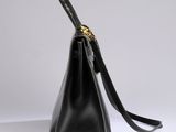 a black leather handbag with a gold clasp on the handle