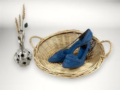 un panier sur lequel sont posées une paire de chaussures bleues, à côté d'un vase