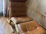 fauteuil inclinable en cuir marron avec repose-pieds, posé sur un sol en bois
