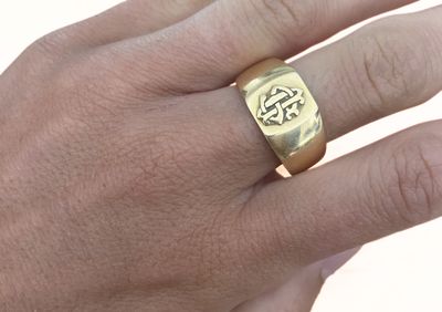 la main d'un homme tenant une bague en or ornée d'une croix