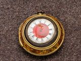 une montre de poche en or avec un cadran rouge