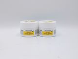 two jars of cream sitting on top of a white surface