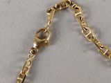 a close up of a gold chain bracelet on a white surface