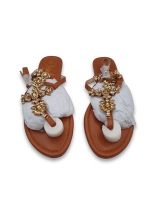 Ces sandales sont en cuir et ornées de perles dorées