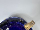 a blue glass vase with a gold handle on a white surface