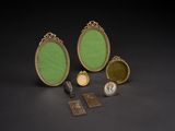 three gold and green oval frames with a key and other items
