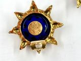 pair of gold and blue glass sunbursts on a white surface