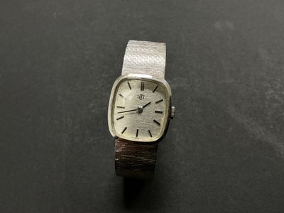 une image représentant une montre posée sur une surface noire, avec un fond noir