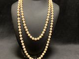 a white pearl necklace on a mannequin with a black background