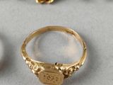 two gold rings and a pearl necklace on a white surface