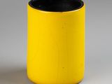 une tasse jaune à bord noir posée sur une surface blanche