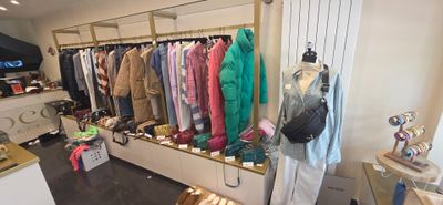 une photo d'un magasin de vêtements avec un portemanteau rempli de vêtements