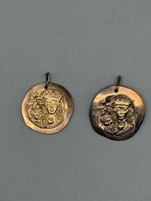 deux pendentifs en forme de pièces d'or représentant le visage d'un homme et d'une femme
