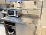un micro-ondes posé sur un plan de travail en inox