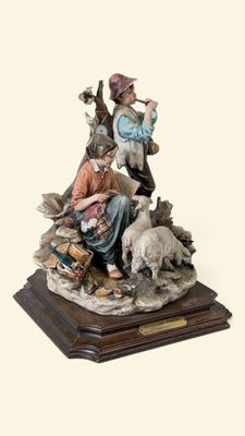 figurine représentant un homme et une femme assis sur un rocher avec un chien