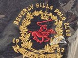 a black shirt with a gold and red emblem on it