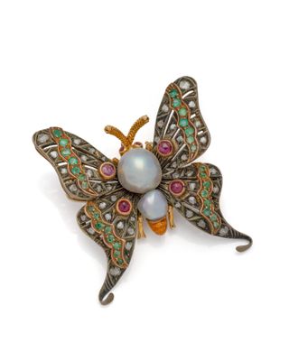 un gros plan sur une broche en forme de papillon ornée de perles et de pierres précieuses